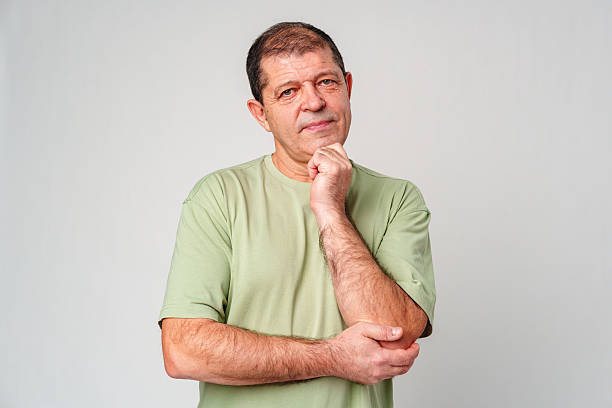 istock A man in a light green shirt and jeans stands against a plain background with a thoughtful expression 2233506346
