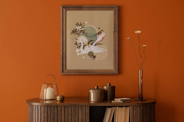 istock Stylized mock up poster with botanical elements above a vintage sideboard and decorations in a warm orange interior. 2233506492