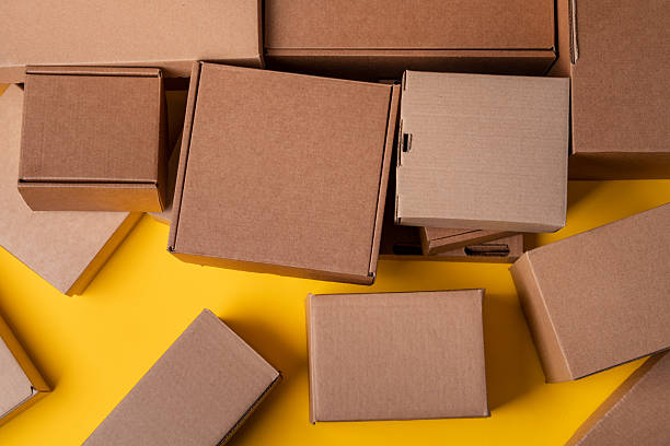istock Beige cardboard boxes on yellow background, close up 2233507448