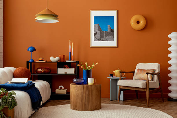 Eclectic interior with orange wall, mock up poster artwork and colorful accents blending modern design with retro charm.