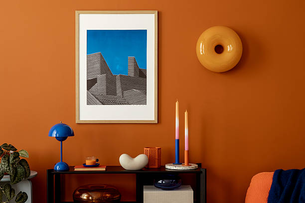 istock Stylish living space with orange wall, architectural mock up artwork, blue lamp and contemporary accessories. 2233507700
