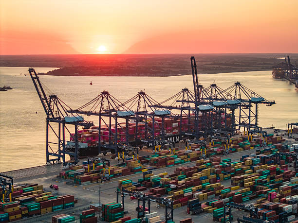 Cargo ship being loaded with containers at felixstowe port, suffolk, england, during a beautiful sunset