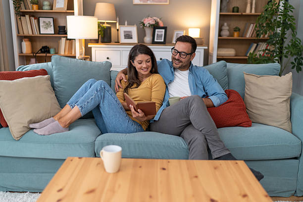 istock Happy couple relaxing on sofa, reading book and drinking coffee 2233510507