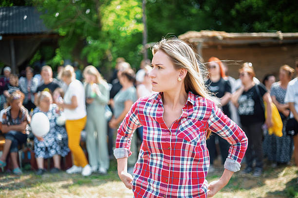 Woman standing with hands on hips and looking away from a crowd of people in a park