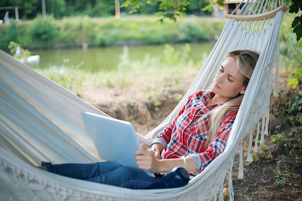 istock Freelancer sleeping in hammock while working on laptop near lake 2233511087