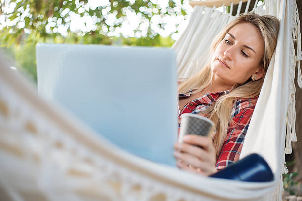 istock Woman relaxing in hammock using laptop and drinking coffee 2233511147