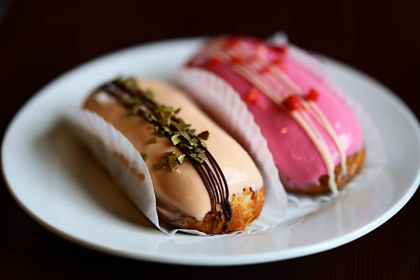 Two sweet donuts on a white plate, topped with colorful icing.