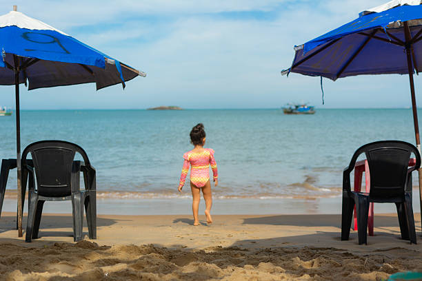 Girl having fun on the beach sand. Jumping the ocean waves.