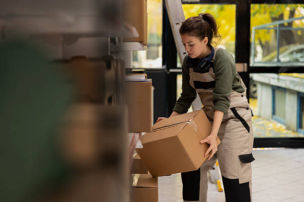 istock Female staff member managing cardboard boxes storage on shelving units 2233520176
