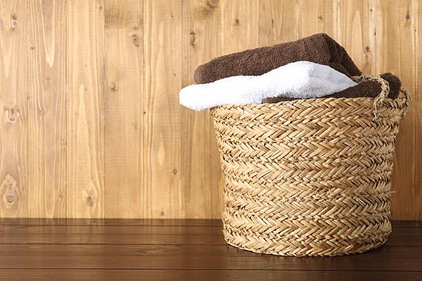 istock Wicker basket full of laundry on wooden table, space for text 2233520197