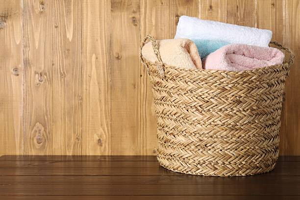 istock Wicker basket full of laundry on wooden table, space for text 2233520319