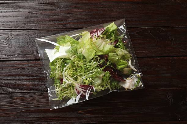 istock Pack of fresh salad mix on wooden table, top view 2233520585
