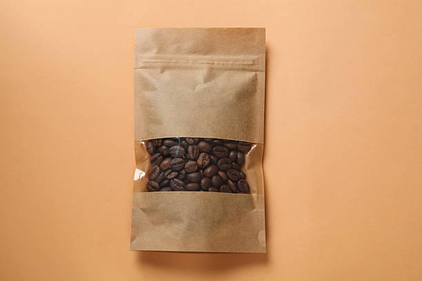 istock Paper pouch bag with coffee beans on color background, top view 2233520612