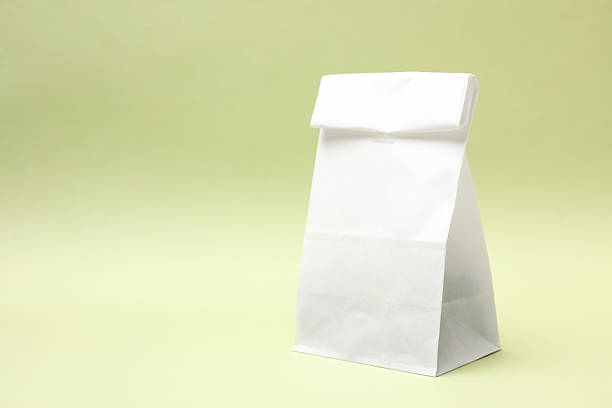 One closed paper bag on light green background. Space for text
