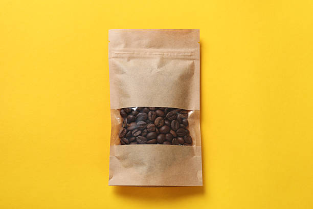 istock Paper pouch bag with coffee beans on yellow background, top view 2233520727