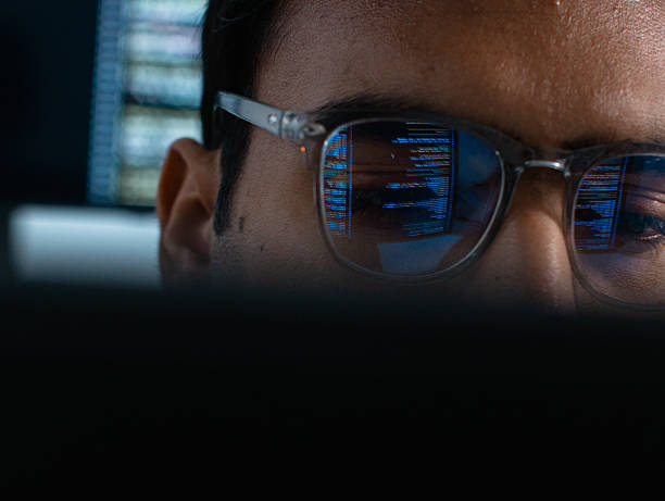 istock Close-up of Indian male computer programmer looking at computer monitor with line of code reflected in eyeglasses, analyzing data, data mining, working on software development, artificial intelligence programming, Ai Machine learning system at tech office 2233522462