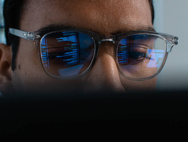 istock Close-up of Indian male computer programmer looking at computer monitor with line of code reflected in eyeglasses, analyzing data, data mining, working on software development, artificial intelligence programming, Ai Machine learning system at tech office 2233522464