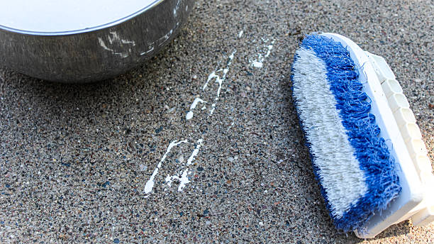 istock A stiff bristle brush by white paint splatter on concrete. Cleanup. 2233523971