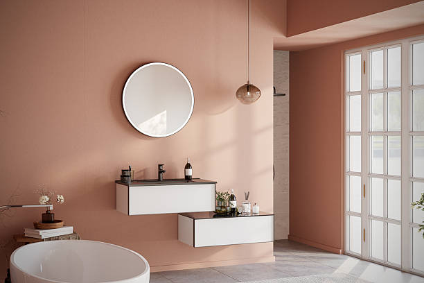 istock Modern minimalist bathroom interior with freestanding bathtub, vanity unit, round mirror, shower area, and natural sunlight. Japandi-inspired cozy design with warm terracotta walls, elegant accessories, and decorative plants. 3D render 2233526296