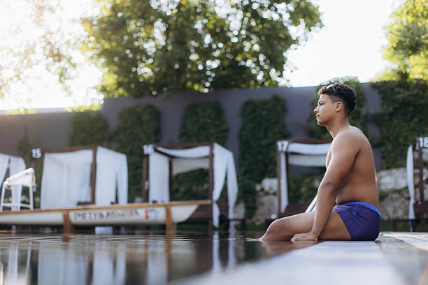 istock Young latino swimmer relaxing by the poolside after training 2233526993