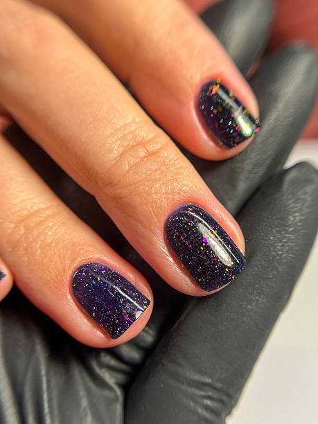 istock Dark glitter gel manicure on short natural nails close up 2233527032