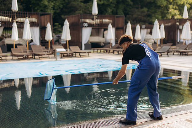 istock Pool cleaner using leaf skimmer during maintenance work in luxury resort 2233527233