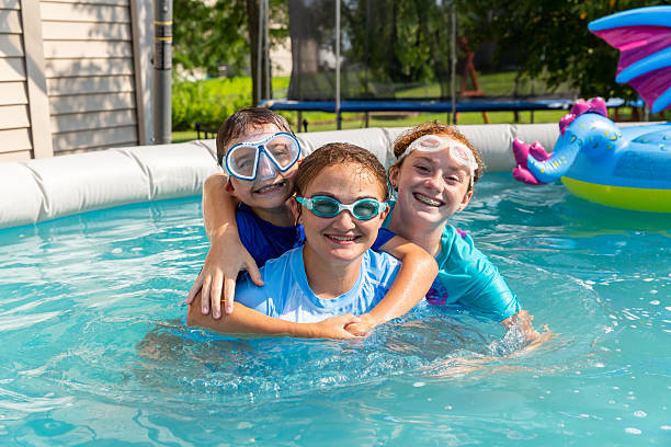 istock Two Sisters & Brother Smiling In Swimming Pool 2233527386