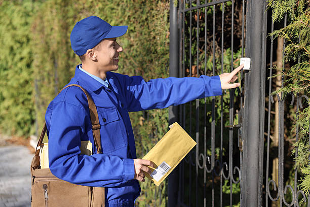 Postman with parcel ringing entrance bell outdoors