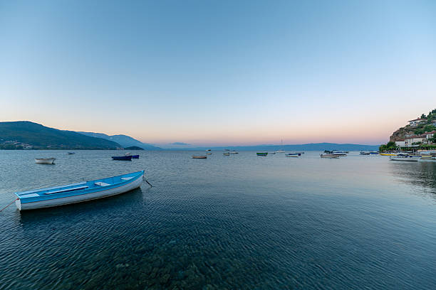 A blue boat on Lake Ohrid. The tranquility of sunrise. A sunrise and lake view suitable for holiday and nature-themed projects.