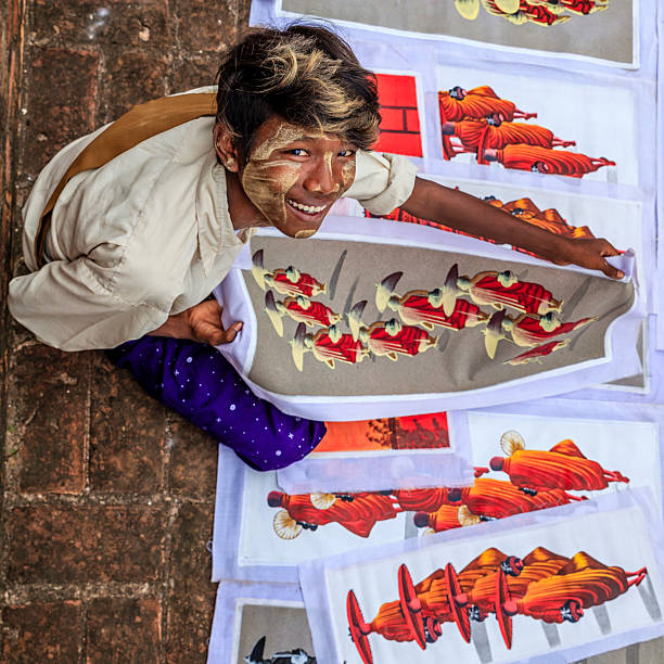 Young Burmese boy with thanaka face paint selling souvenirs - sand paintings, in the ancient temple of Bagan, Myanmar (Burma)