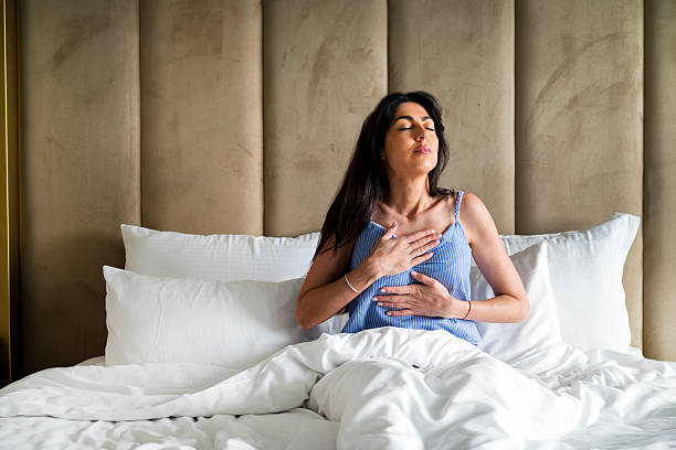 istock Young Woman Practicing Breathing Exercise in bed for Relaxation 2233530541