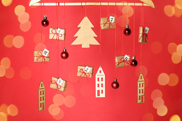 Handmade advent calendar and decor hanging on red background with blurred lights