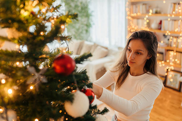 istock Young woman decorating Christmas tree at home 2233530697
