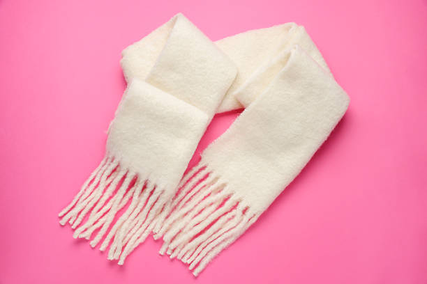 Warm woolen scarf on pink background, top view