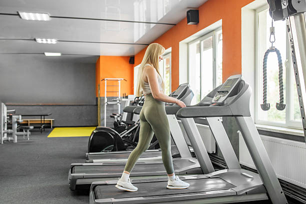 istock Woman walking on treadmill in bright gym 2233536873