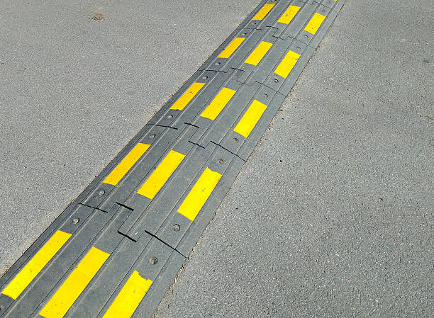 istock A top-down view shows an asphalt road with a rubber speed bump marked with bright yellow stripes. This obstacle emphasizes the need to observe road safety and is a crucial element of urban infrastructure. 2233540619