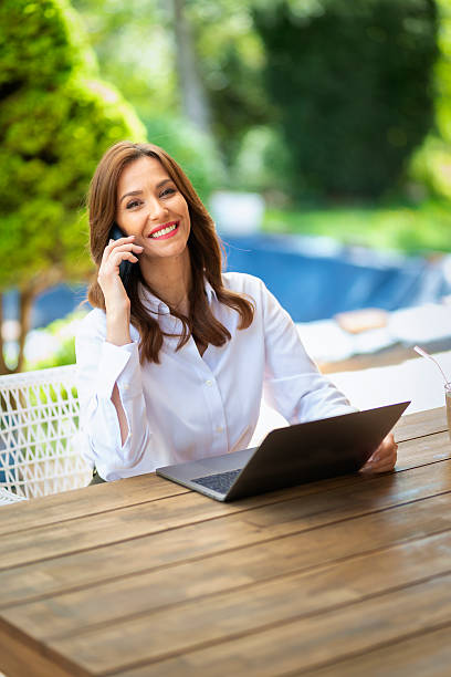 istock Confident mature woman using computer laptop and smartphone and working from in the balcony 2233540692