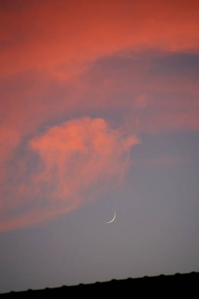 istock a very small crescent moon in a cloudy sky at sunset 2233541621