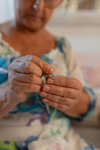 istock Senior woman threading a needle for sewing 2233543631