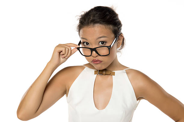Woman peeking over glasses with skeptical expression, studio shot on white background