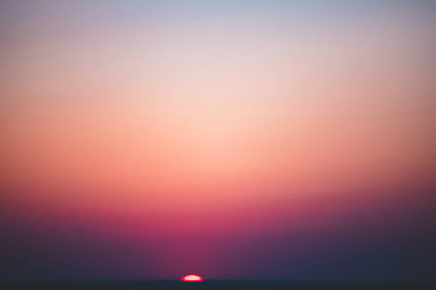 A vivid golden hour sky during sunset, featuring soft pastel gradients from deep orange to cool blue. Perfect for backgrounds, nature concepts, or tranquil landscape themes. Captured during the golden hour to emphasize natural light and smooth color transitions