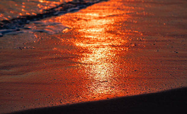istock A serene sunset reflecting brilliantly on a sandy shore during low tide 2233546284