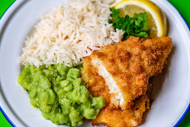 London UK, September 03 2025, Breaded Cod Fillet With Boiled White Rice and Mushy Peas