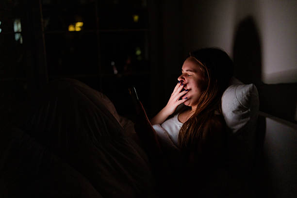 istock Sleepy girl illuminated by phone screen at night 2233554050