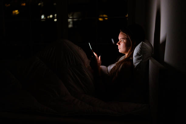 istock Young woman awake at midnight scrolling device 2233554060
