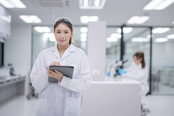 istock Femail scientist wearing a lab coat holding a tablet and smiling in a modern laboratory 2233554104
