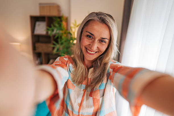 istock Smiling woman taking selfie at home with blurred background 2233554496