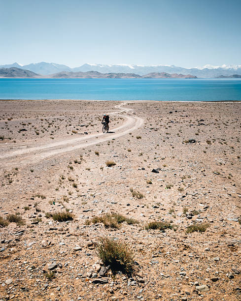 Bicyclist rides road to remote lake, Bikepacking Pamir Highway
