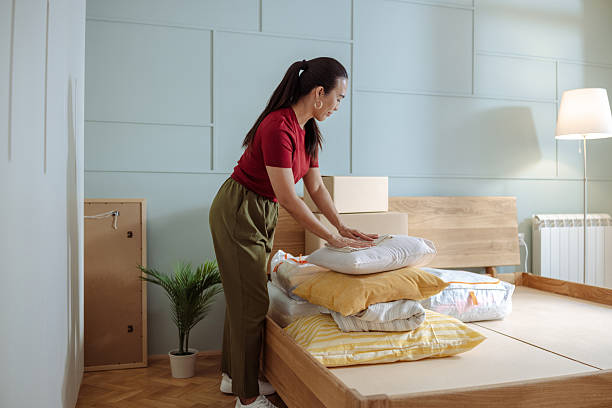 How to find Top-Rated Vacation Rental Cleaning Services in Moorpark, CA 2 Woman organizing bed linens in a cozy, modern bedroom with wooden furniture A woman arranges a stack of pillows and linens on a bed in a softly lit, modern bedroom, showcasing organization and comfort. Rental Cleaning.
