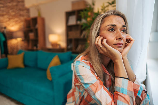 istock Sad woman looking out the window at home 2233556184